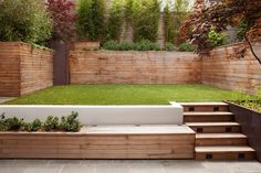 an outdoor garden with wooden steps leading up to the grass area and trees in the background