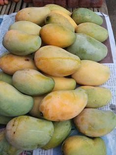 a pile of mangoes sitting on top of a newspaper