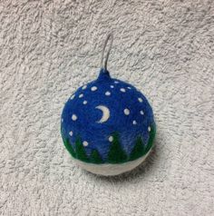 a blue ornament with white stars and trees on it, hanging from a hook