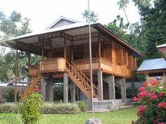 a wooden house sitting on top of a lush green field next to flowers and trees