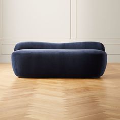 a blue couch sitting on top of a hard wood floor next to a white wall