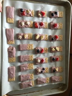 a tray filled with crackers covered in pink frosting