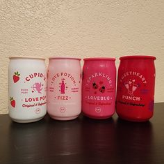 five cups lined up on a table with the lids painted pink, red, and white