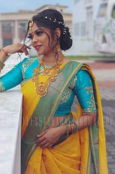 a woman in a yellow and blue sari with jewelry on her head, posing for the camera