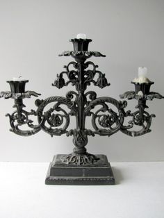 an ornate black candle holder with three candles