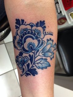 a blue and white flower tattoo on the leg