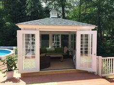 a gazebo sitting on top of a wooden deck next to a swimming pool in a backyard