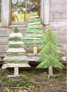 three wooden christmas trees sitting in front of a window on the side of a building