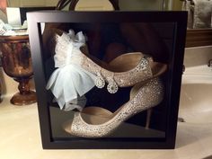 a pair of high heeled shoes are displayed in a shadow box on a bathroom counter