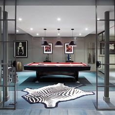 a pool table in the middle of a room with pictures on the wall and zebra rug