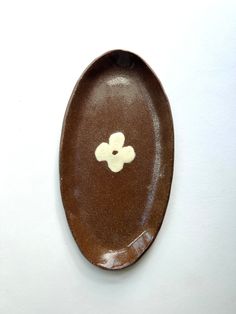 a brown plate with a white flower on it