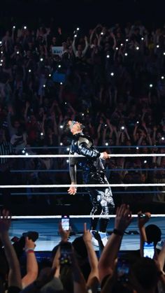 the man is standing in front of an audience with his arms raised up and one hand on his hip