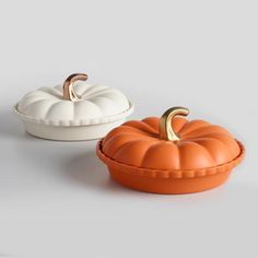 two pumpkin shaped dishes sitting next to each other