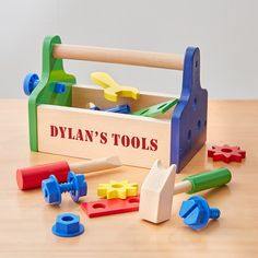 a wooden tool box filled with toys on top of a wood table next to a pair of hammers