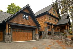 a large house with two garages and stone walls