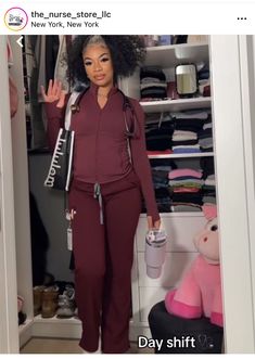 a woman standing in front of a closet holding a cup and giving the peace sign