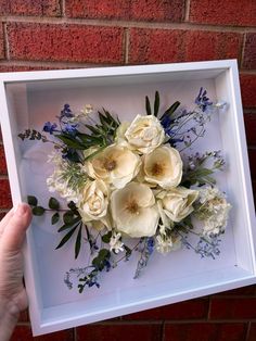 a person holding up a white box with flowers in it