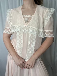 Details: maxi length; not lined, semi-sheer; white lace detail around hemline, waist, bust, neckline and sleeves; v-neckline with lace panel detail; cape/bib overlay detail; no zip closure.  Damage: small blemish to front right hand side of skirt (not noticeable) otherwise no clear damage, excellent vintage condition.  Shoulders: 15 in // Bust: 42 in // Waist (dropped): 40 in // Sleeves: 11.5 in // Overall Length: 52 in Please note all inventory is pre-loved and sold as is. I will always do my a Feminine V-neck Delicate Lace Top, Fitted V-neck Lace Top With Lace Collar, White Feminine Lace Top With Lace Trim, White Lace Top With Contrast Lace, Spring V-neck Lace Top With Lace Trim, Fitted Feminine Lace Top With Contrast Lace, Feminine Fitted Lace Top With Contrast Lace, Spring V-neck Lace Top With Delicate Lace, Spring Delicate Lace V-neck Top