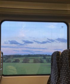 a view out the window of a train car with trees and grass in the background