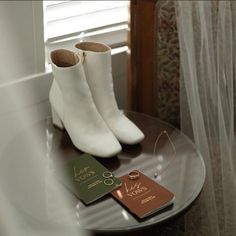 a pair of white boots sitting on top of a wooden table next to a book