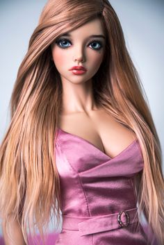 a barbie doll with long blonde hair and blue eyes wearing a pink dress, posing for the camera