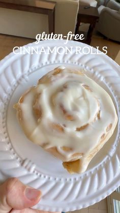 a person holding a white plate with a cinnamon roll on it and the text gluten - free cinnamon rolls