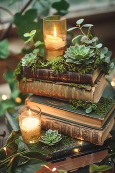 three books stacked on top of each other next to a candle and some greenery