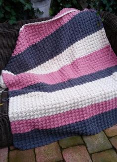 a crocheted blanket sitting on top of a wicker chair