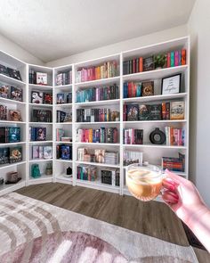 a person holding a wine glass in front of a bookshelf filled with books