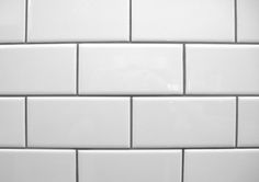 a white tiled bathroom wall with no one in it