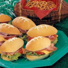 several sandwiches on plates with pretzels in the basket and other food items around them