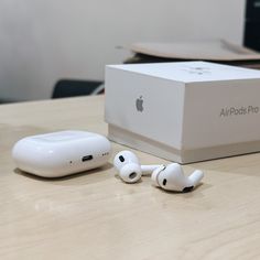 an apple airpods pro sitting on top of a wooden table next to a box