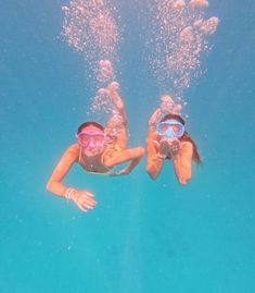 two people are swimming in the water with snorkels on their heads and one person is wearing goggles