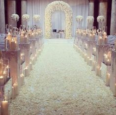 the aisle is decorated with white flowers and candles