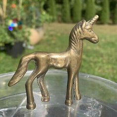 a small metal toy horse sitting on top of a glass bowl