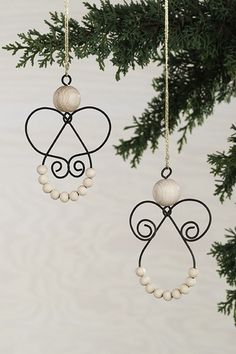 an ornament hanging from a tree branch with beads and pearls in the shape of angel wings