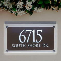 a black and white sign that reads, 615 south shore dr with flowers in the background