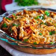 a casserole dish with meat and vegetables in it sitting on a tablecloth