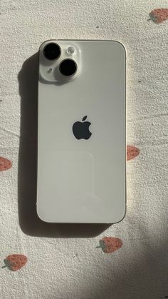 an apple phone is sitting on a bed with the camera attached to it's back