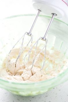 two whisk attachments in a bowl filled with whipped cream on a counter