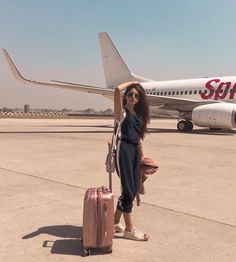 a woman standing in front of an airplane with her luggage