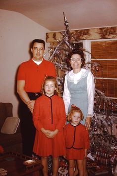 a family poses in front of a christmas tree