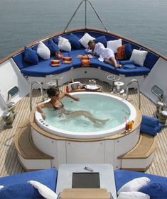 a woman in a large jacuzzi on a boat with blue cushions and pillows