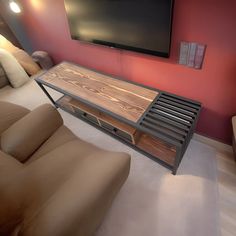 a flat screen tv mounted to the side of a wall next to a brown couch