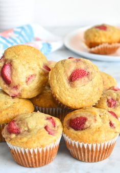 a pile of muffins sitting on top of a white table next to plates