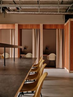 an empty conference room with long tables and chairs in the foreground, two large wooden partitions on either side