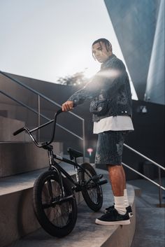 a man standing next to his bike on some steps