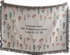 a white wall hanging with flowers and the words consider how the wildflowers grow luke 12 22 - 28