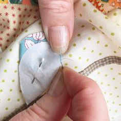 a person is stitching on fabric with a sewing needle and thread in their hand