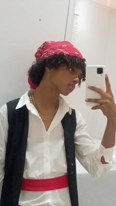 a man wearing a red bandana taking a selfie in the mirror with his cell phone